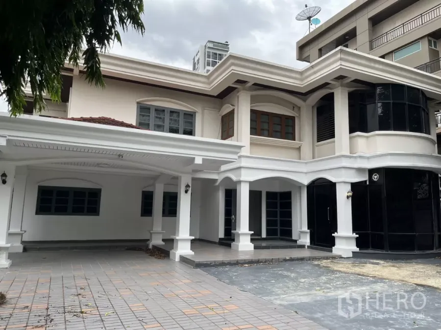 บ้าน ให้เช่าในWatthana, Bangkok - บ้านเดี่ยวสองชั้นย่านวัฒนา โดดเด่นด้วยซุ้มโค้งสีขาว กระจกกรอบสีดำ และที่จอดรถในร่ม.