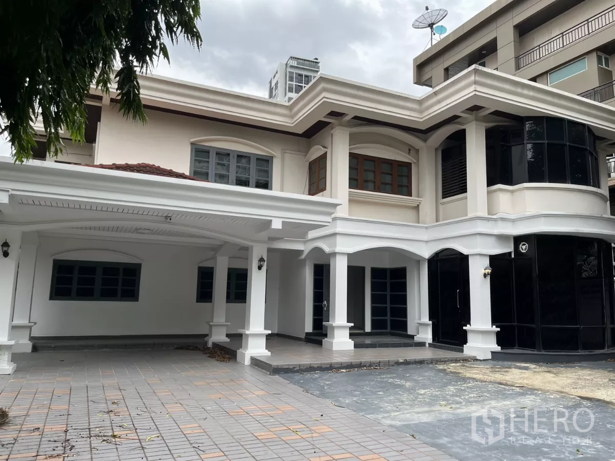 บ้าน ให้เช่าในWatthana, Bangkok - บ้านเดี่ยวสองชั้นย่านวัฒนา โดดเด่นด้วยซุ้มโค้งสีขาว กระจกกรอบสีดำ และที่จอดรถในร่ม.