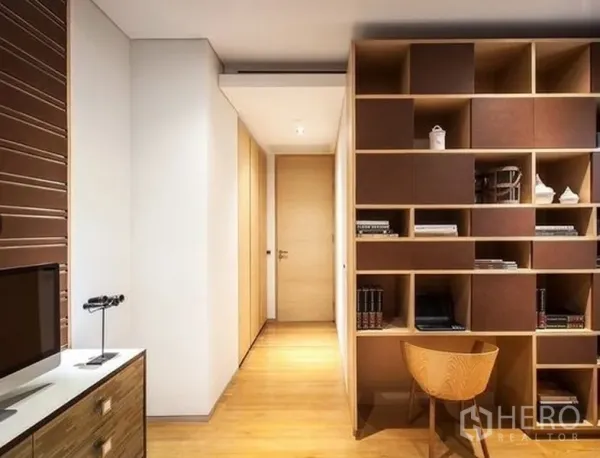 公寓 出租在Bang Rak, Bangkok - 走廊书写角，带大面积内置书架与木质装饰，旁有电视柜。