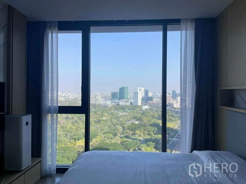 公寓 出租 - 床边大画幅窗户，远望绿色公园与天际线。