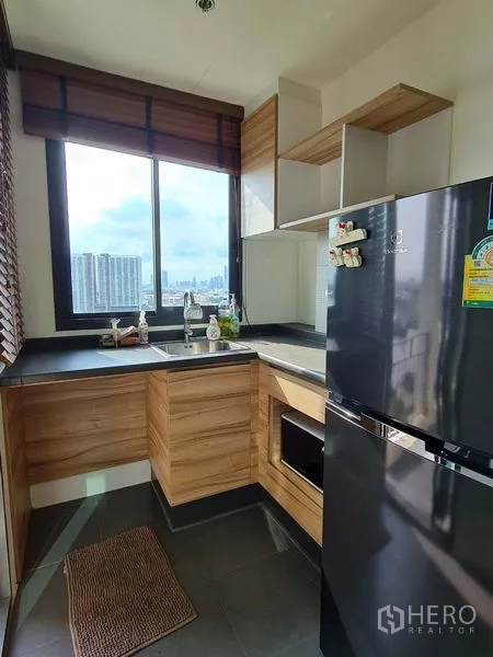 公寓 出租或出售在Yan Nawa, Bangkok - 独立L形厨房，设窗户、黑色台面、木质橱柜与冰箱，可观城市天际线。