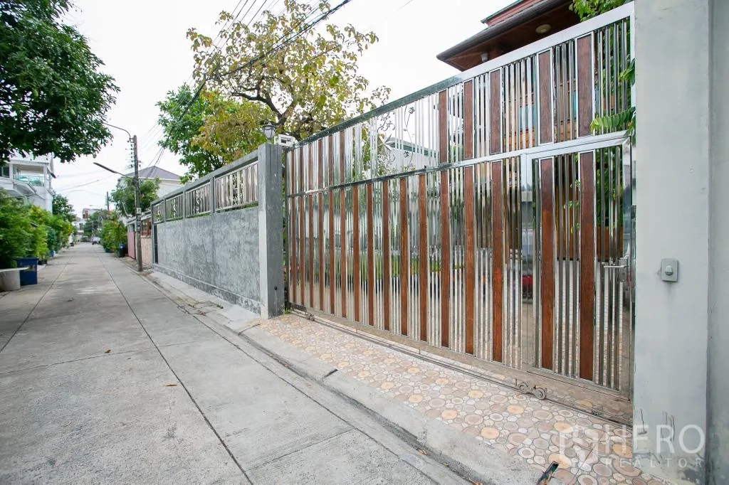 Detached House for rent or sale in Huai Khwang, Bangkok - Quiet lane view of tall stainless and wood sliding entrance gate to the property.