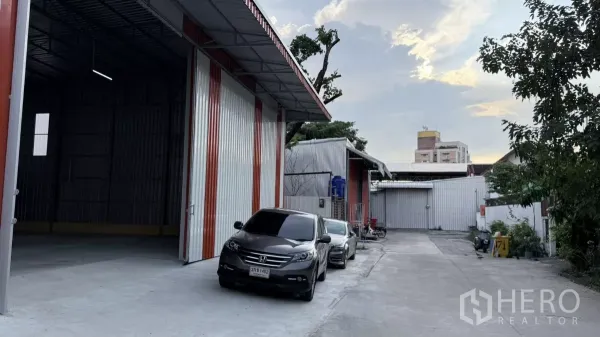 Warehouse for rent in Wang Thonglang, Bangkok - Driveway beside the warehouse with open bay and multiple parking spaces in a quiet compound.