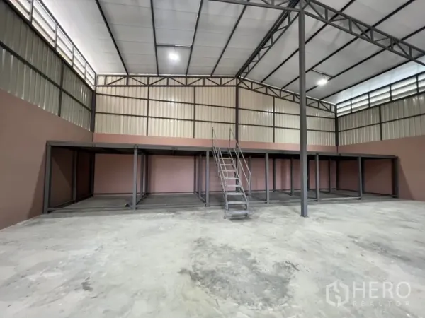 Warehouse for rent in Bang Bua Thong, Nonthaburi - Spacious warehouse interior showing high ceiling, steel trusses and mezzanine with stairs.