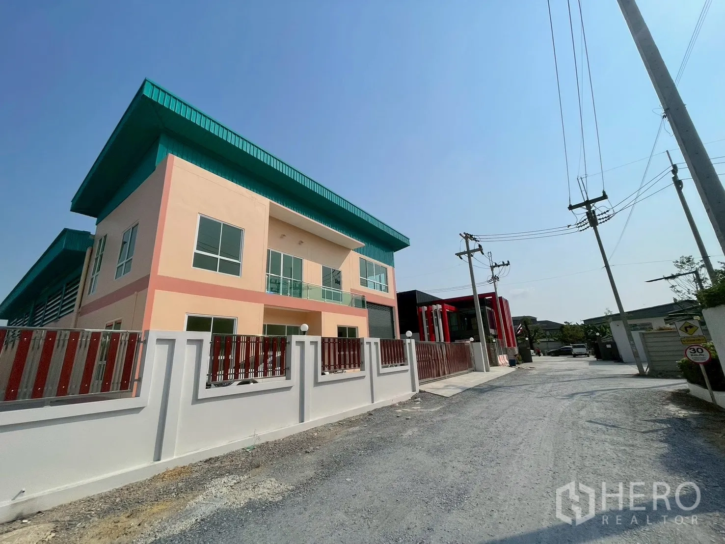 โรงงาน for sale in Sam Phran, Nakhon Pathom - มุมถนนเห็นตัวอาคารโรงงาน กำแพงรั้ว และชายคาสีเขียว