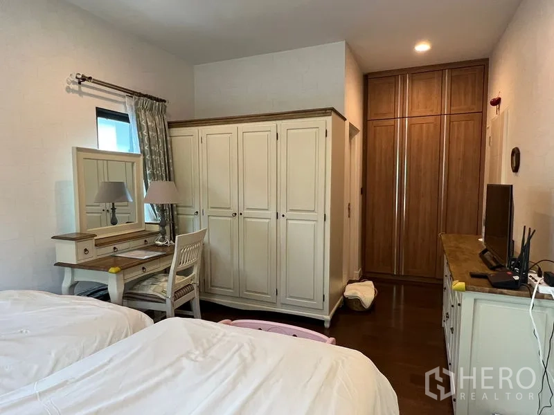Detached House for sale in Bang Kapi, Bangkok - Bedroom corner featuring classic white wardrobes, a vanity desk and built-in storage.