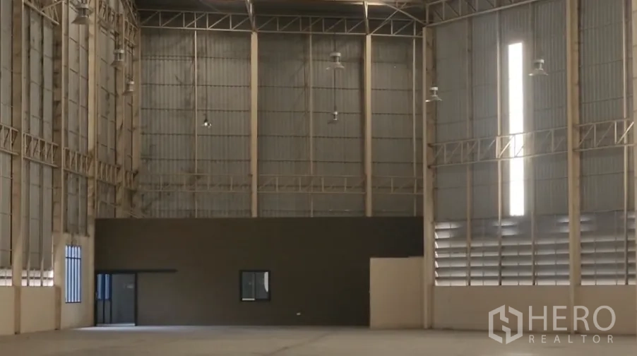 Warehouse for rent in Mueang Samut Sakhon, Samut Sakhon - Warehouse corner with internal office room, tall windows, high ceiling lighting, and steel wall panels.