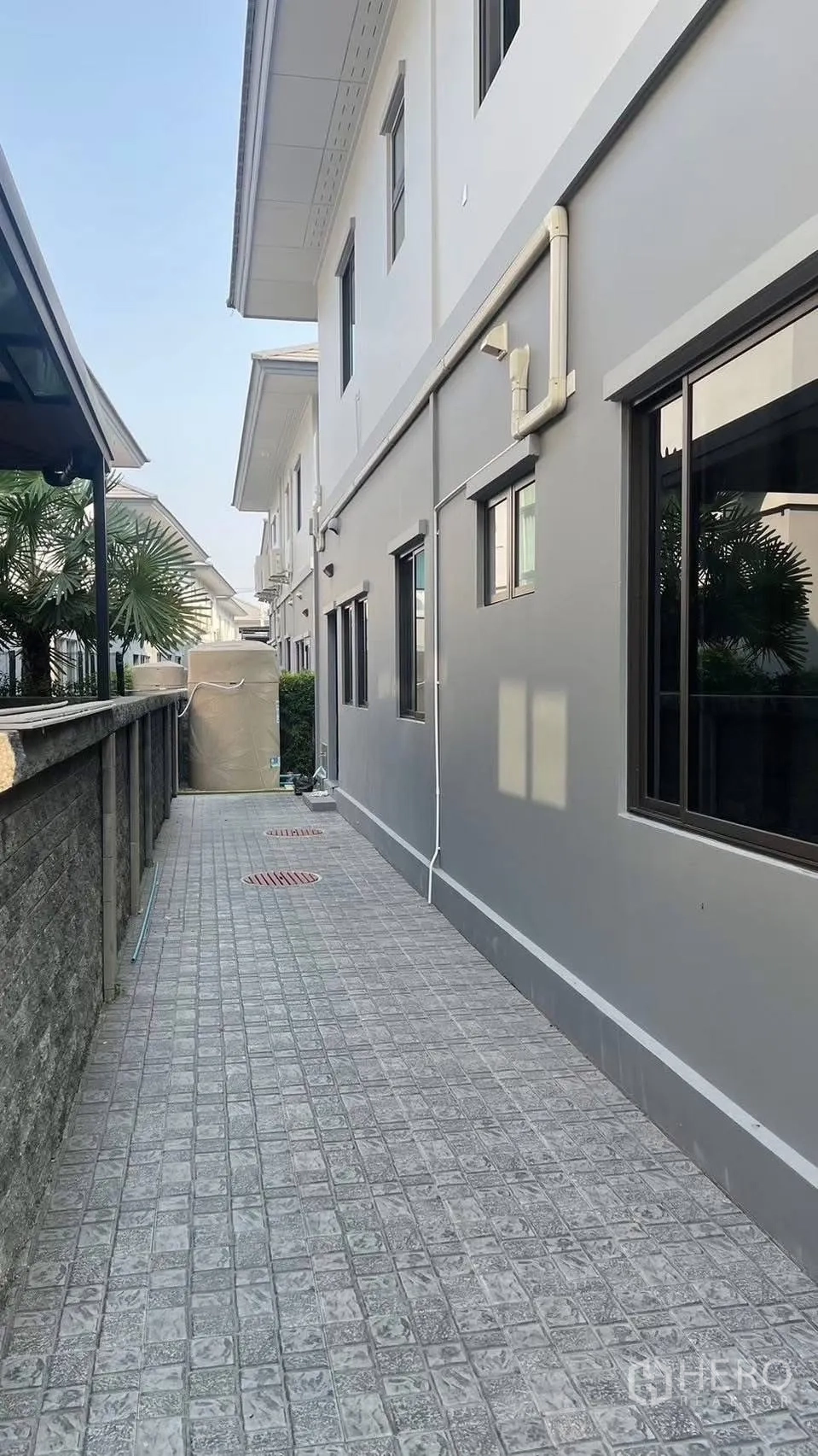 Detached House for rent in Prawet, Bangkok - Side walkway along the house with tiled path and windows.