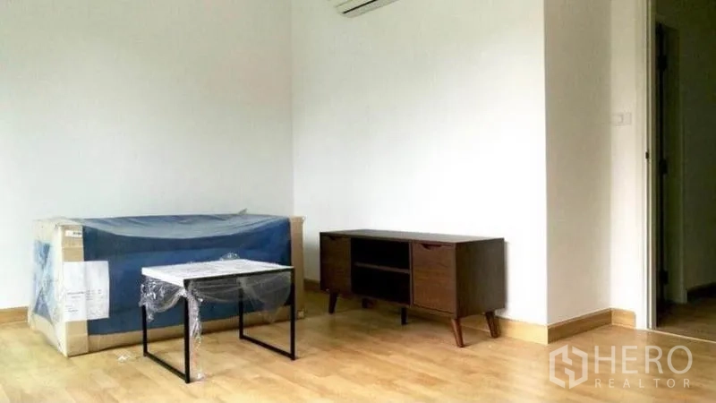 Townhouse for rent in Wang Thonglang, Bangkok - Semi-furnished upper floor living space with wood flooring, TV console, and air conditioner.