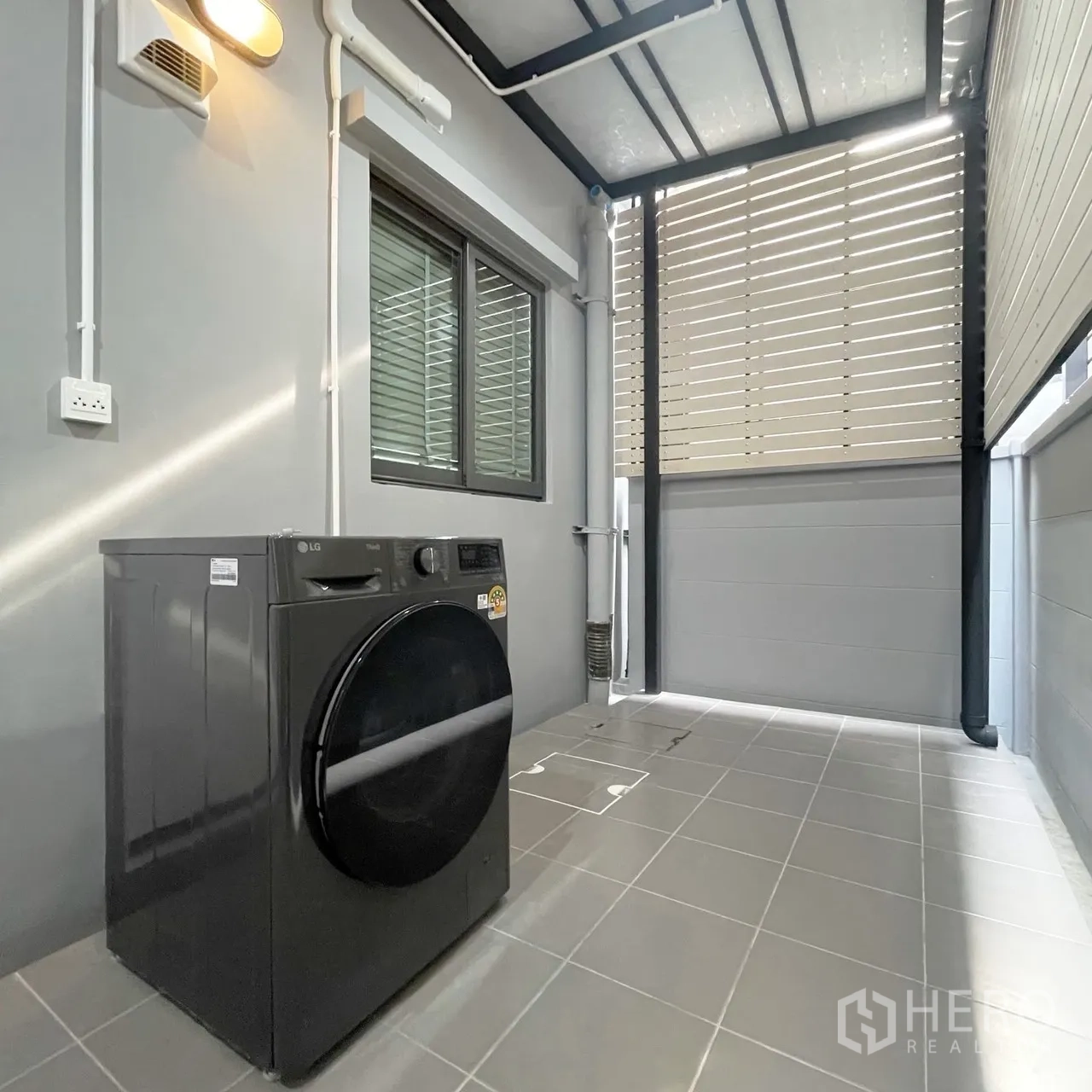 Townhouse for rent in Bang Phli, Samut Prakan - Covered back patio laundry area with a front-load washing machine and louvered privacy screen.