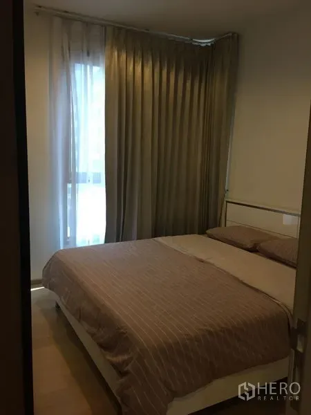 公寓 出租在Watthana, Bangkok - 卧室配双人床与落地窗帘，自然采光柔和