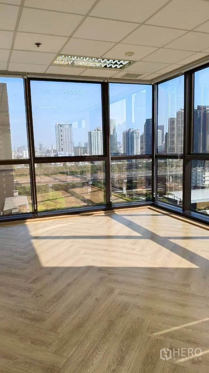 办公空间 for rent in Ratchathewi, Bangkok - 纵向照片，阳光洒在角落落地窗旁的木地板上，城市景色