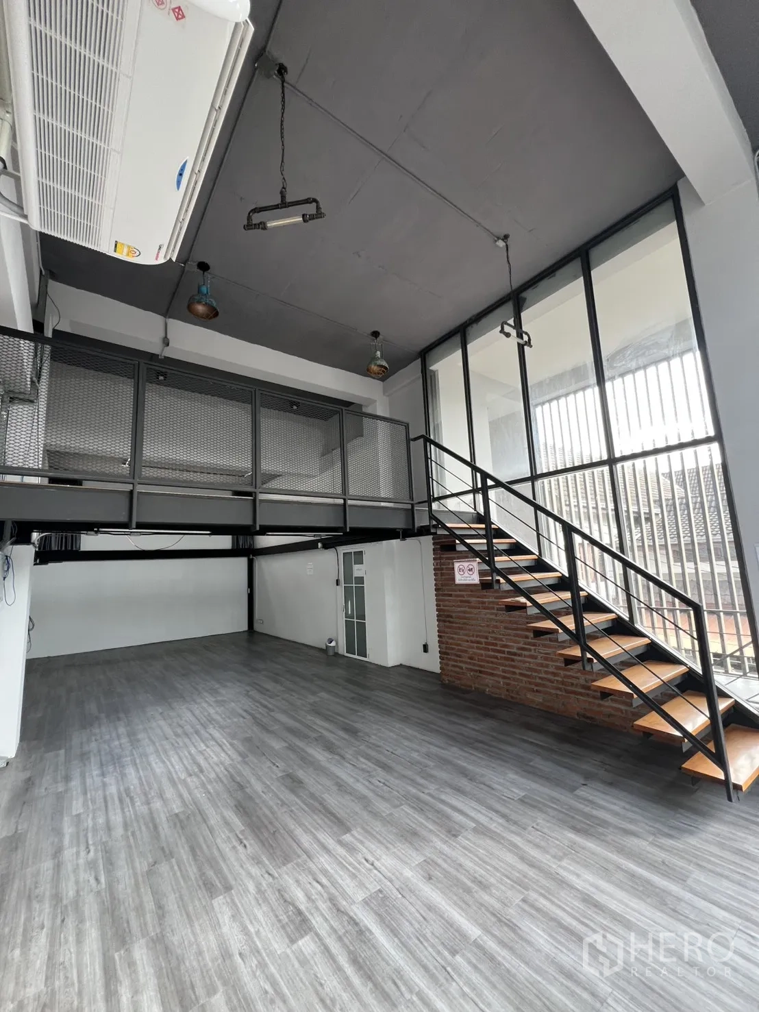 Home Office for rent in Mueang Nonthaburi, Nonthaburi - Double-height workspace with mezzanine, steel staircase and grey vinyl flooring.
