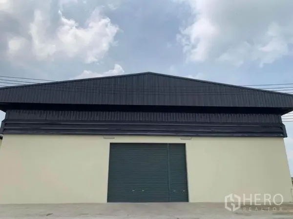 Warehouse for rent in Bang Bo, Samut Prakan - Front exterior of the warehouse with a large roller shutter door and wide driveway.