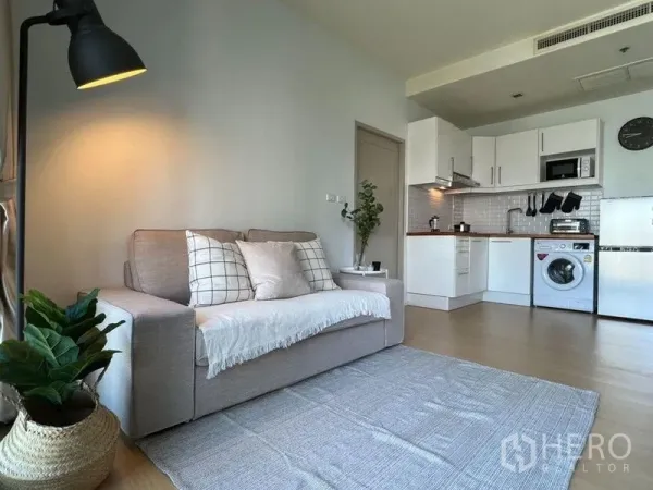 คอนโด ขายในWatthana, Bangkok - ห้องนั่งเล่นสว่างของคอนโดเอกมัย มีโซฟา โคมไฟ และครัวเปิดพร้อมเครื่องซักผ้า