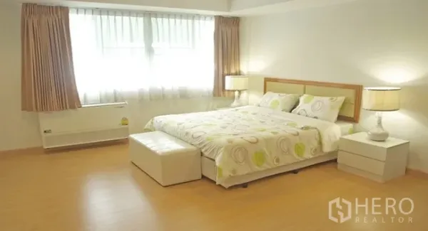 อพาร์ทเมนท์ ให้เช่าในKhlong Toei, Bangkok - ห้องนอนใหญ่กว้างหน้าต่างบานใหญ่ ม่านสีอบอุ่น และที่นั่งปลายเตียง