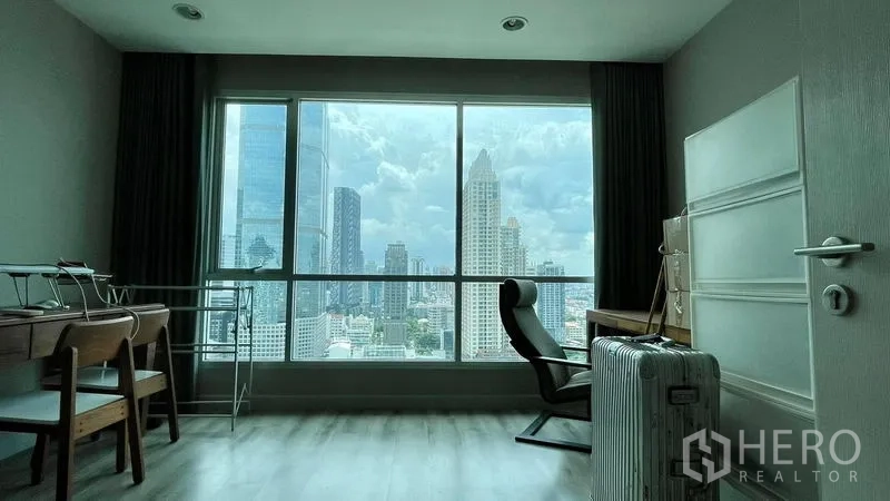 公寓 出售在Sathon, Bangkok - 明亮房间可作卧室或书房，书桌与椅子面对大幅窗外的曼谷天际线。