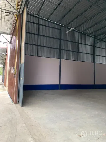 货栈 出租在Saphan Sung, Bangkok - 大型金属推拉门通向仓库，带有遮蔽装卸区和高挑金属屋顶。
