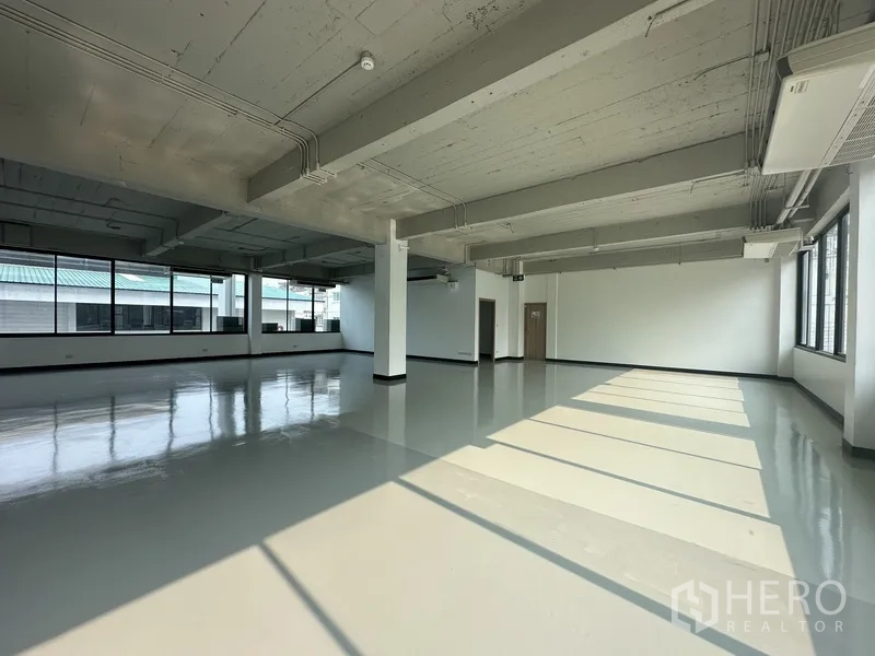 Office Space for rent - Sunlit open office with large windows casting long shadows across the floor.