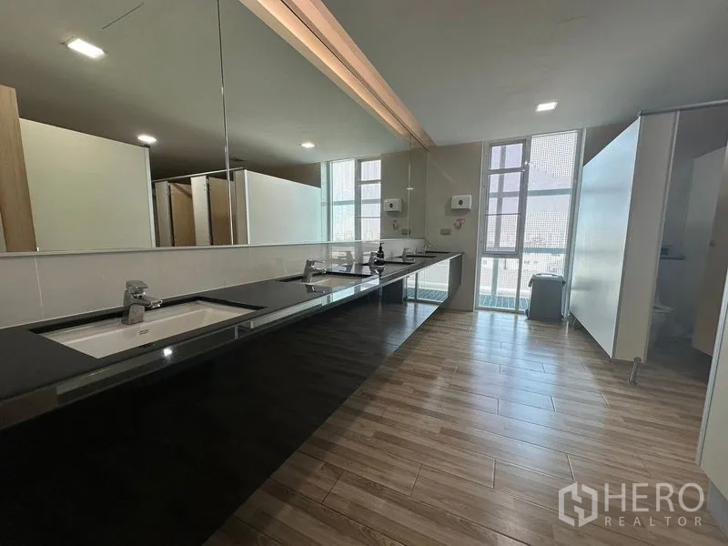 Office Space for rent - Modern restroom with long black countertop, large mirror and multiple stalls.