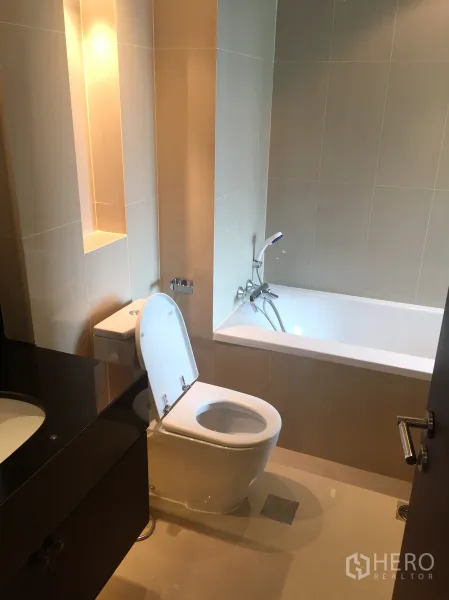 Condominium for rent in Sathon, Bangkok - Contemporary bathroom with bathtub, handheld shower, vanity and soft ambient lighting.