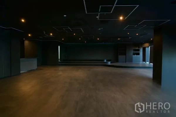 零售空间 出租 - 大型零售大厅，深色吊顶、筒灯照明与升高舞台。