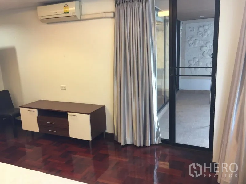 公寓 出租在Khlong Toei, Bangkok - 卧室一角设电视柜与遮光窗帘，玻璃推门通向包阳台