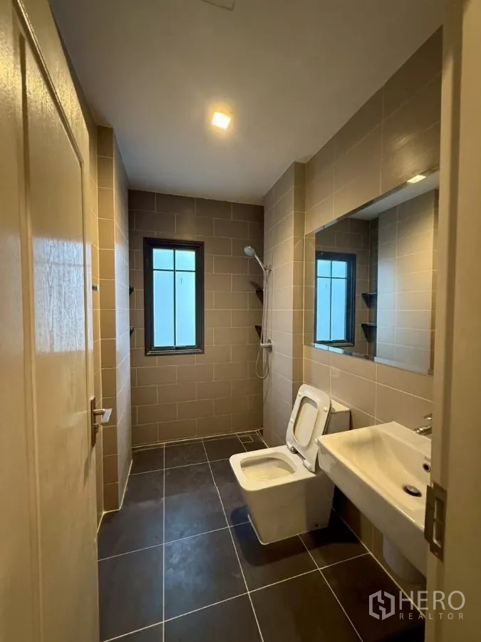 Detached House for rent or sale in Bang Phli, Samut Prakan - Guest bathroom with window, walk‑in shower, toilet and wide vanity mirror.