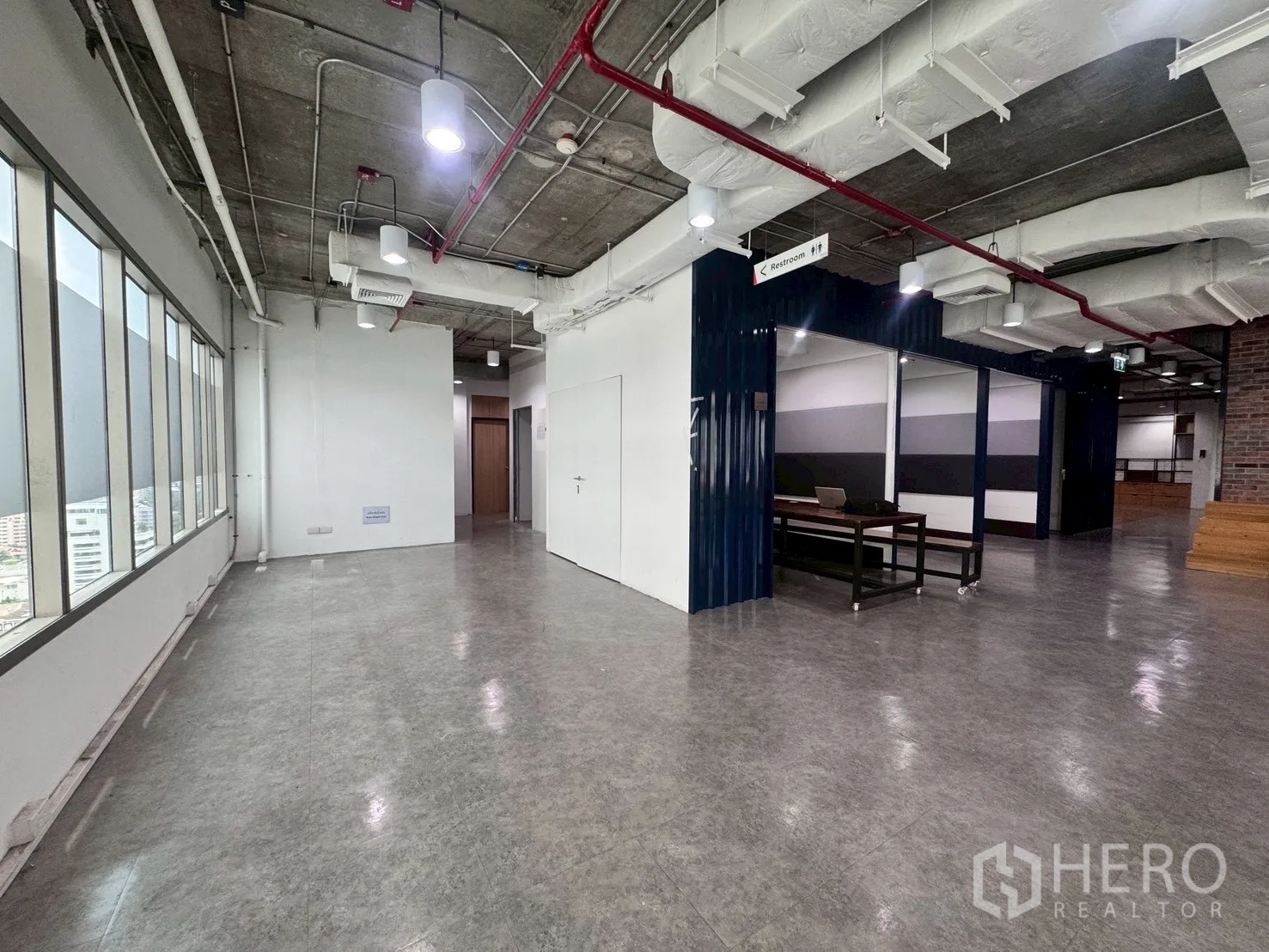 办公室 for rent in Watthana, Bangkok - 转角工作区，长窗与光亮地面并通往内侧房间。