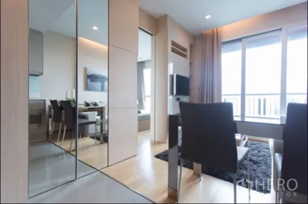 Condominium for rent in Ratchathewi, Bangkok - Dining space with mirrored panels, wood floors and large sliding doors to the balcony.