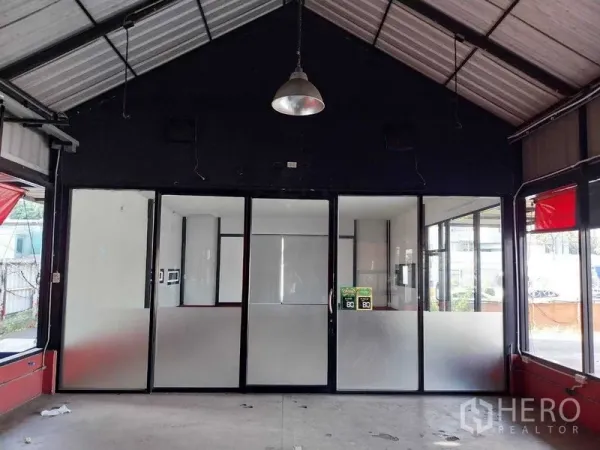 零售空间 出租在Khlong Toei, Bangkok - 空堤区高挑商铺内景，带磨砂玻璃隔断、吊灯、水泥地和临街橱窗。