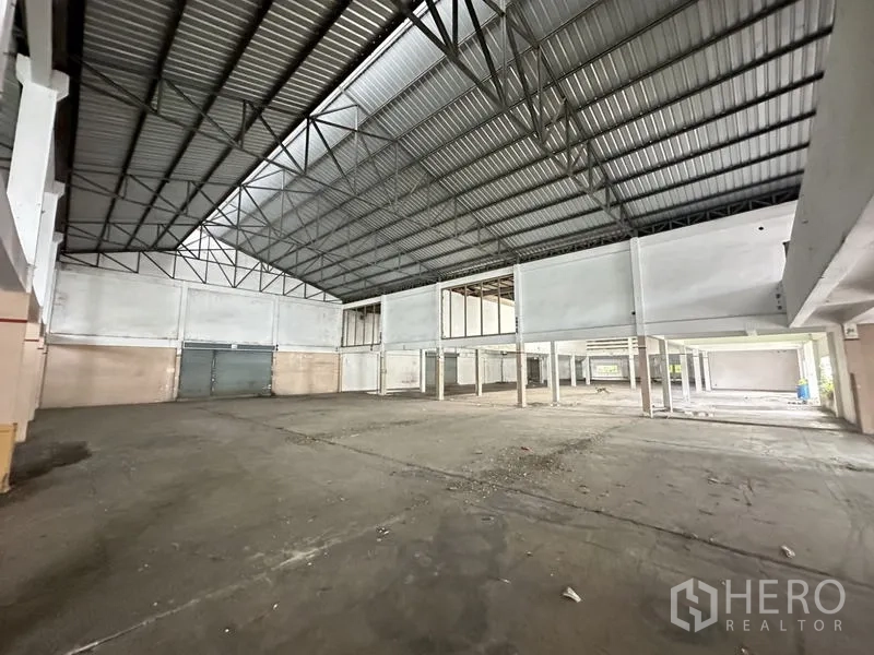 Factory for rent or sale in Khlong Luang, Pathum Thani - Spacious production hall with high steel truss roof and loading doors.