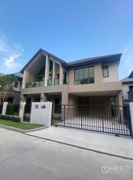 Detached House for rent in Lak Si, Bangkok - Modern two-storey detached house with tall gable roof, double-height windows and a gated driveway.