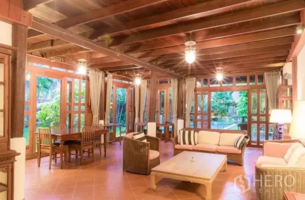 บ้าน ให้เช่าในBang Na, Bangkok - ห้องนั่งเล่นและทานอาหารกว้างสไตล์ไทย งานไม้ทั้งหลัง พื้นกระเบื้อง สีเอิร์ธโทน และหน้าต่างบานใหญ่เห็นวิวสวนในบางนา