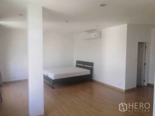 Townhouse for rent in Wang Thonglang, Bangkok - Spacious bedroom with air-conditioning, white walls and wood floors in a Wang Thonglang townhouse.