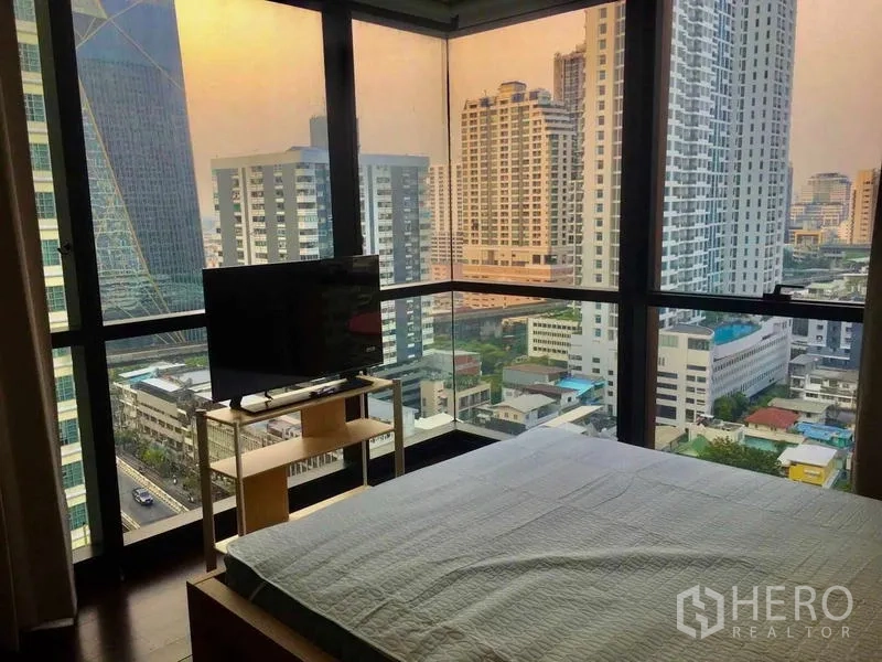 คอนโด ให้เช่า - ห้องนอนมุมอาคารพร้อมกระจกพาโนรามา เตียงนอนและชั้นวางทีวี มองเห็นวิวเมือง