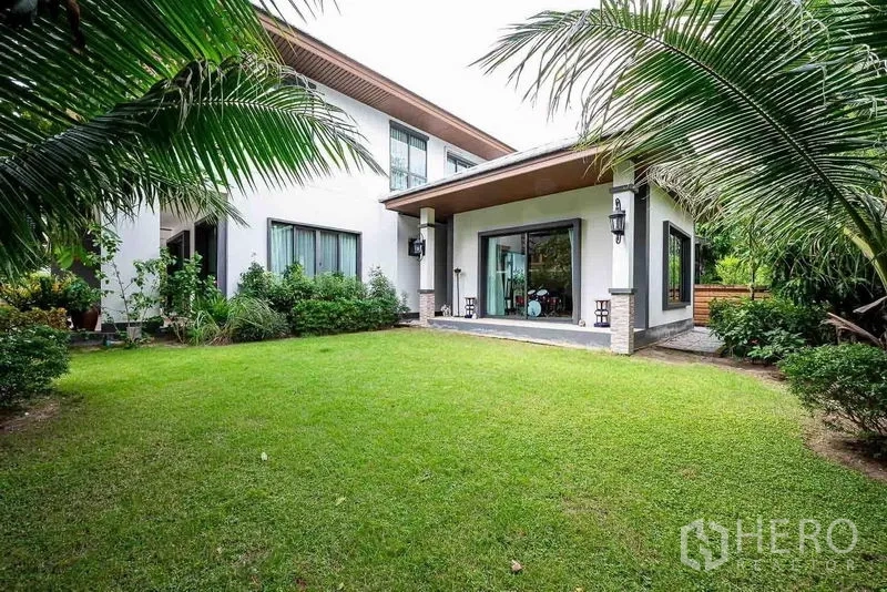 Detached House for sale in Prawet, Bangkok - Lush backyard lawn with covered terrace and sliding glass doors of the house.