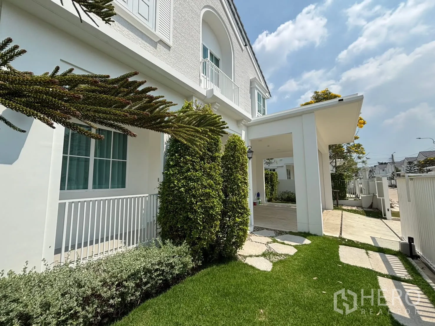 独栋房屋 for rent in Bang Phli, Samut Prakan - 房前花园与带顶车棚，房屋外立面洁白。