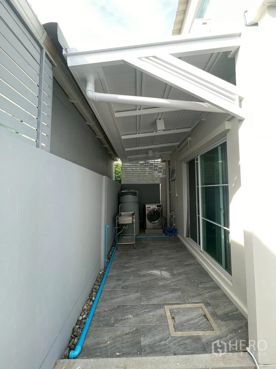 Townhouse for rent in Bang Phli, Samut Prakan - Covered utility area with sink, water tank and washing machine by sliding door.