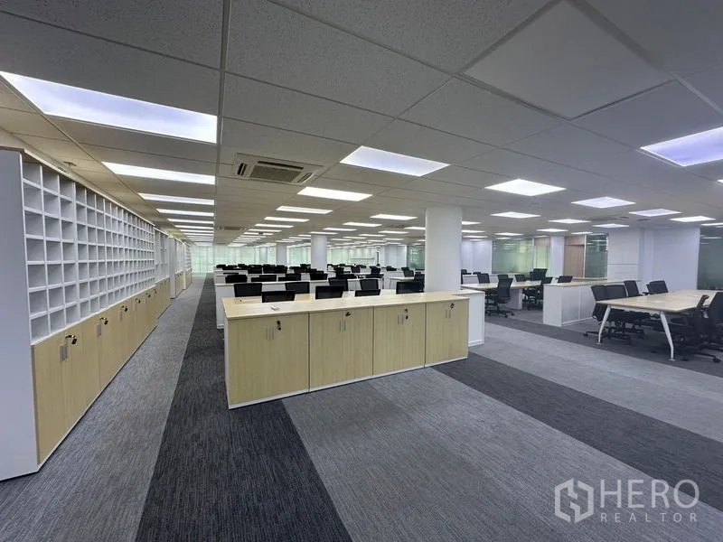 Office Space for rent - Open-plan office with rows of workstations, storage cabinets and carpet flooring.