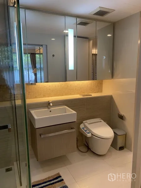 Condominium for rent in Watthana, Bangkok - Modern bathroom featuring mirrored cabinets, a square basin, bidet toilet, and glass shower enclosure.