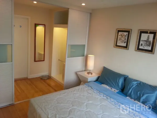 Condominium for rent in Ratchathewi, Bangkok - Bedroom featuring blue bedding, framed art and a built-in sliding wardrobe.