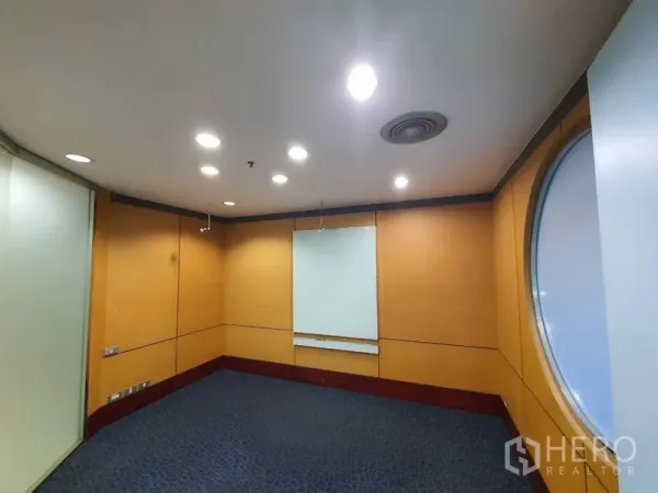 Office Space for rent in Watthana, Bangkok - Compact meeting room with wood panel walls, recessed lighting and a round window.