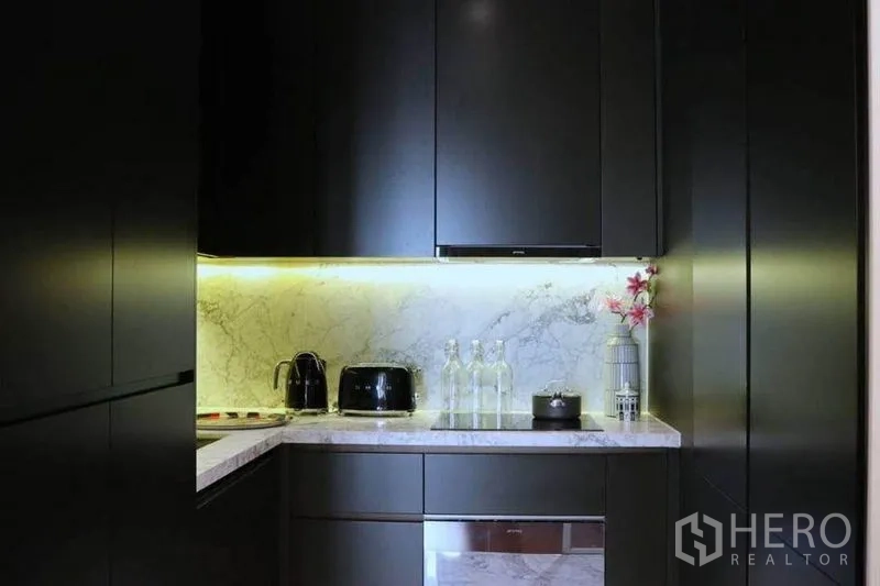公寓 出租在Watthana, Bangkok - 紧凑现代厨房，深色橱柜、大理石挡板与橱下灯。