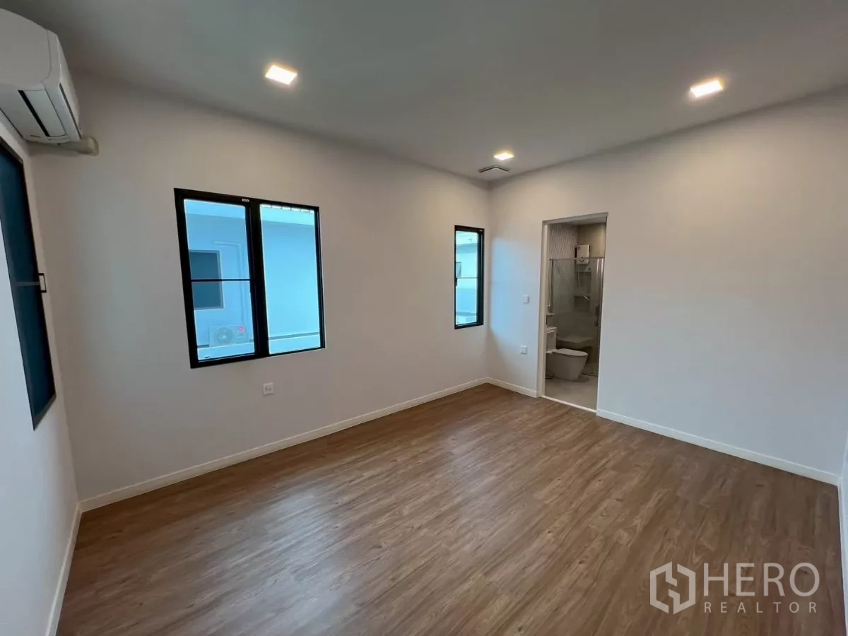 Detached House for rent in Samut Prakan - Bedroom with entry to ensuite bathroom and multiple windows.