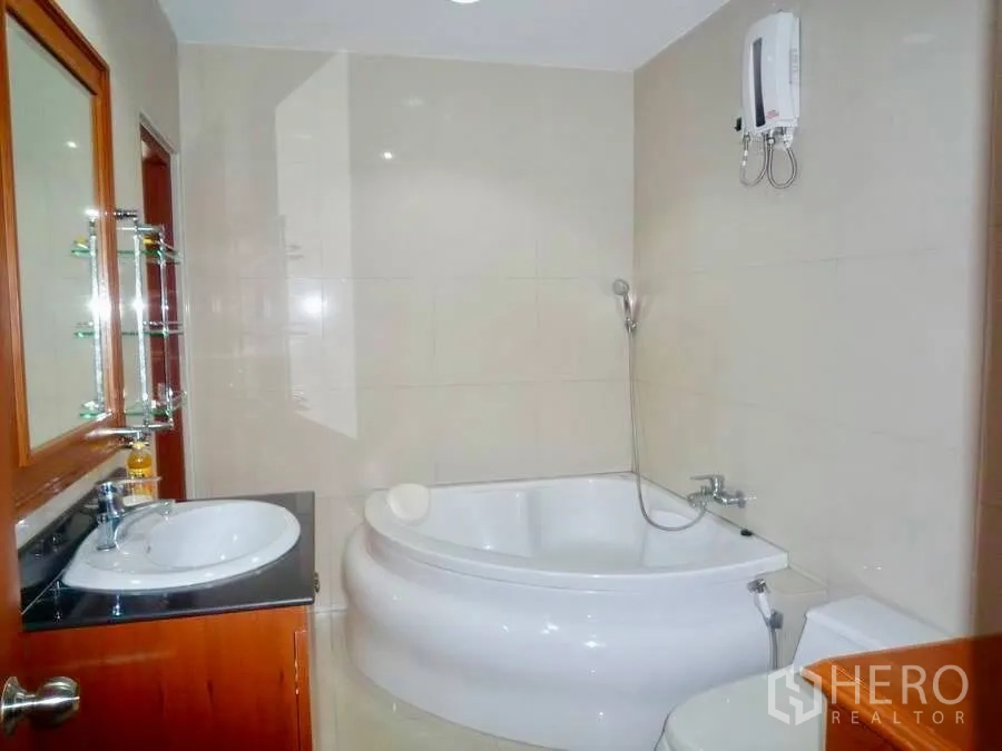 Townhouse for rent in Khlong Toei, Bangkok - Modern bathroom with corner bathtub, vanity, toilet and water heater.