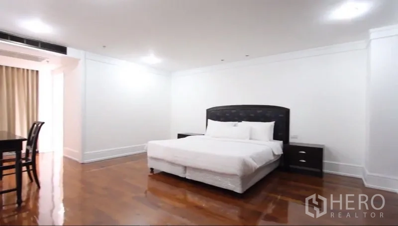 房间 出租在Khlong Toei, Bangkok - 宽敞主卧，特大床、床头柜与抛光木地板。