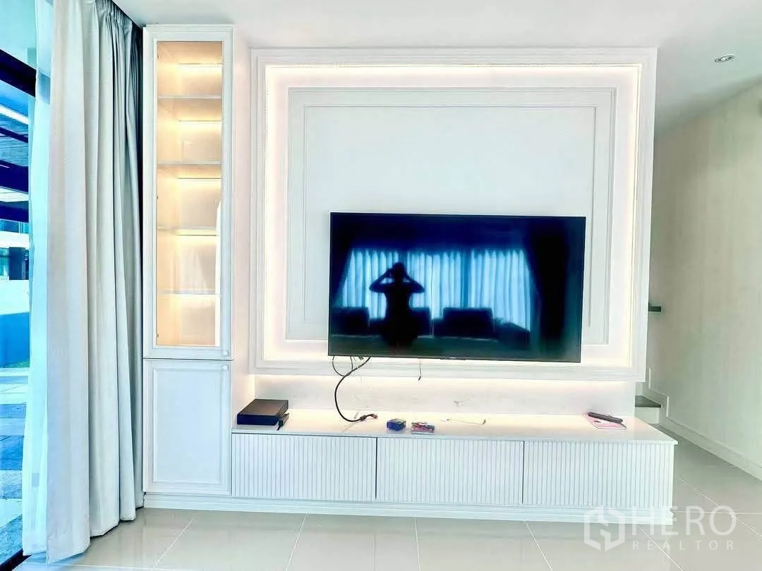 Detached House for rent in Bang Kapi, Bangkok - Living room TV feature wall with display cabinet and LED lighting.