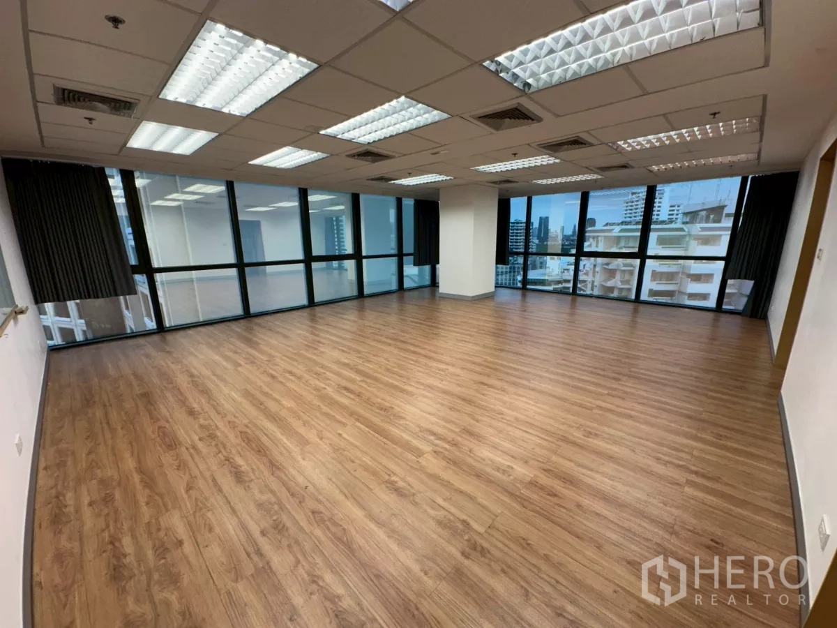 Office Space for rent in Khlong Toei, Bangkok - Sunlit office area with wide windows on two sides and wood floors.