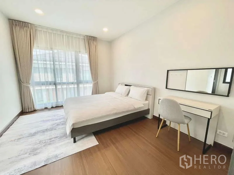 Detached House for rent in Bang Phli, Samut Prakan - Guest bedroom with bed, vanity desk and wide window with curtains.